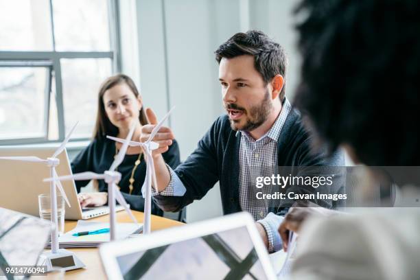 businessman explaining wind turbine models to colleagues in office - business responsibility stock pictures, royalty-free photos & images