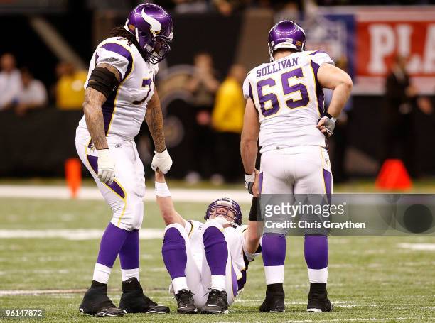 Brett Favre of the Minnesota Vikings is helped up by teammates Phil Loadholt and John Sullivan after he took a hard hit in the second half against...