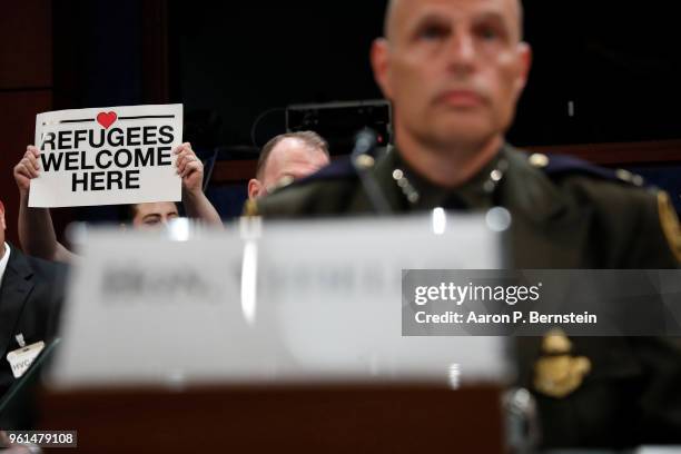 Demonstrator holds a sign as Ronald Vitiello, acting deputy commissioner of U.S. Customs and Border Protection testifies before the House Homeland...