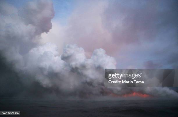 Steam plume rises as lava glows as it enters the Pacific Ocean at dawn, after flowing to the water from a Kilauea volcano fissure, on Hawaii's Big...