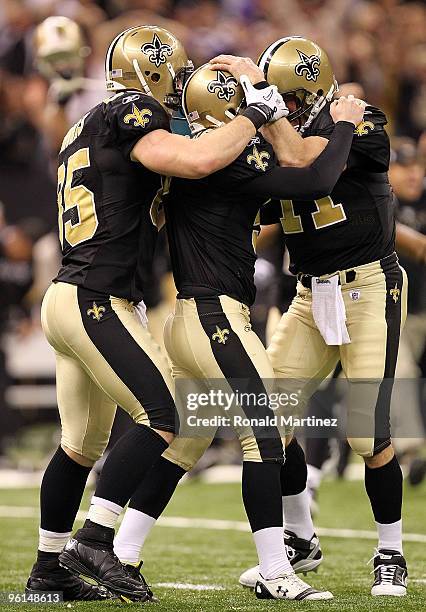 Kicker Garrett Hartley of the New Orleans Saints celebrates with teammates David Thomas and Mark Brunell after kicking a 40-yard game-winning field...