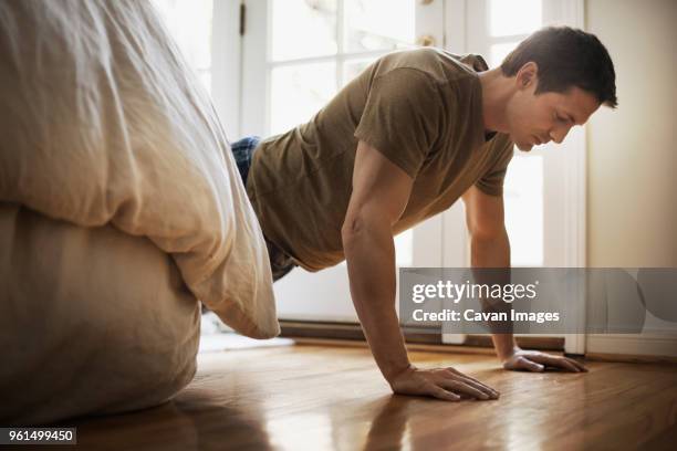 man doing push-ups in bedroom at home - opdrukken stockfoto's en -beelden