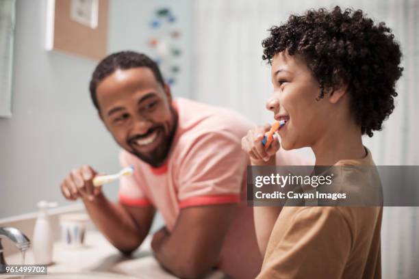 happy father and son brushing teeth in bathroom - lavarsi i denti foto e immagini stock