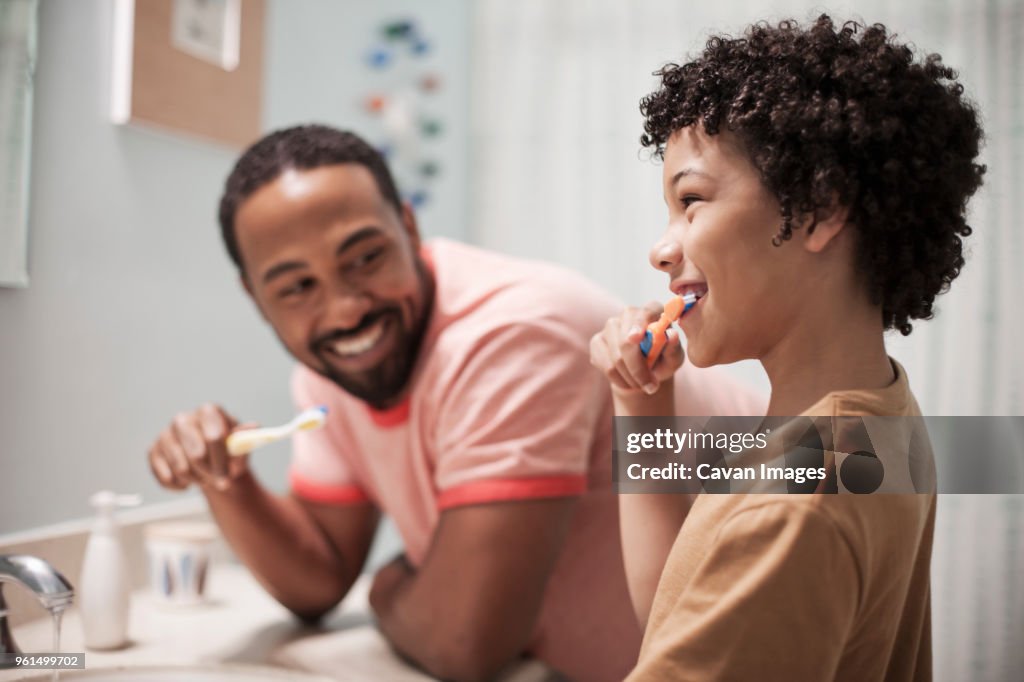 Happy father and son brushing teeth in bathroom