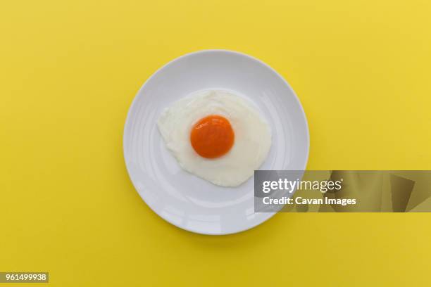 overhead view of fried egg in plate on yellow background - sunny side up stock pictures, royalty-free photos & images