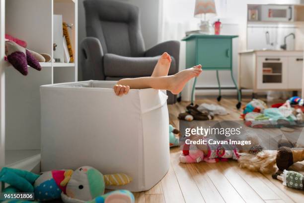 low section of girl in cardboard box at home - kids mess stockfoto's en -beelden