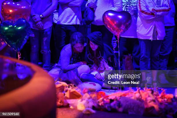 Two women sit among the floral tributes and balloons exactly one year after the bomb detonated, on the first anniversary of the terrorist attack in...