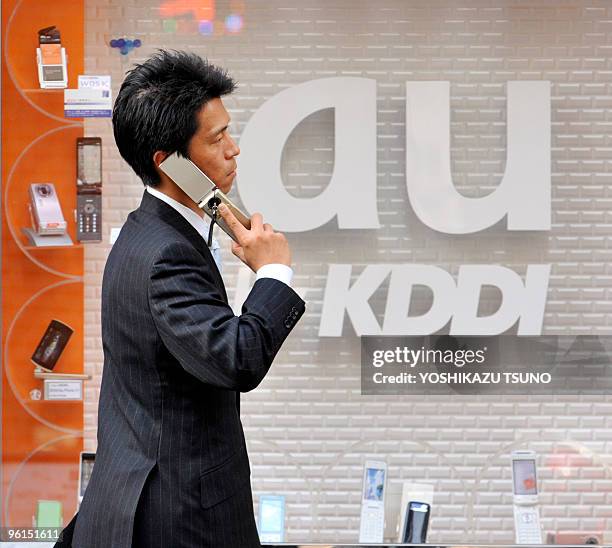 Man uses his mobile phone before a cellular shop of Japan's telecommunication giant KDDI in Tokyo on January 25, 2010. KDDI's net profit for the...