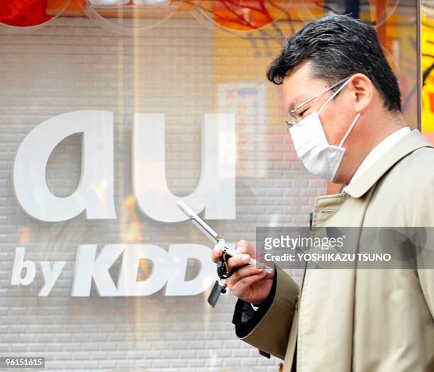 Businessman uses his mobile phone before a cellular shop of Japan's telecommunication giant KDDI in Tokyo on January 25, 2010. KDDI's net profit for...