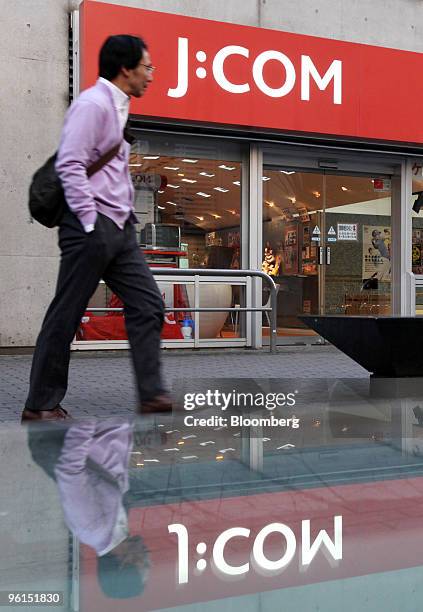 Pedestrian walks past Jupiter Telecommunications Co.'s J:COM shop in Tokyo, Japan, on Monday, Jan. 25, 2010. KDDI Corp., Japan's second-biggest...