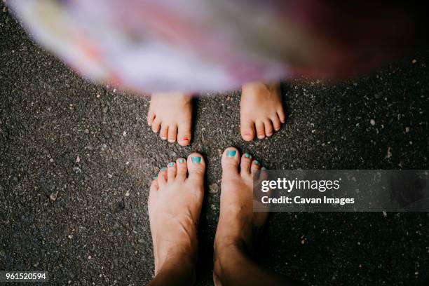 low section of mother and daughter standing on asphalt - family with one child mother bonding family adult daughter focus on background leisure stock-fotos und bilder