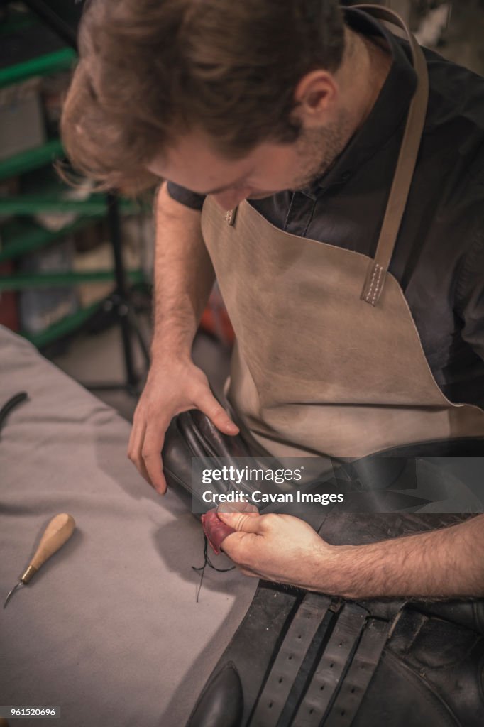 High angle view of shoemaker making shoes at workbench in workshop