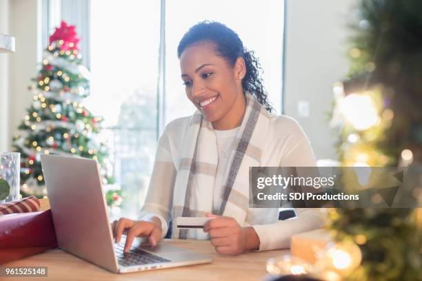 mitte erwachsene frau genießt weihnachtseinkäufe online von zu hause aus - african american woman with money stock-fotos und bilder