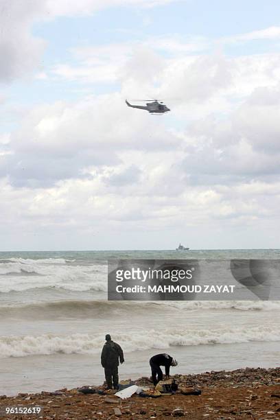 Lebanese army helicopter scans the sea as two men inspect the debris of an Ethiopian Boeing 737 that crashed off the Lebanese coast, south of the...