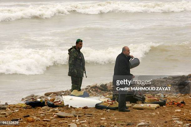 Lebanese army soldier stands next to a man inspecting the debris from an Ethiopian Boeing 737 that crashed off the Lebanese coast, south of the...