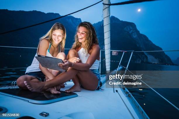 frauen genießen flitterwochen auf segelboot - tablet paar sommer stock-fotos und bilder