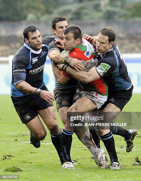 Biarritz's center Laurent Tranier fights for the ball with Glasgow's Max Evans, Grame Morrison and Thom Evans, during their European Cup rugby match...