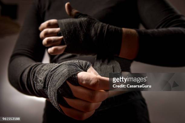 junge frau boxer schützenden verband um ihre handgelenke zu binden - boxer stock-fotos und bilder