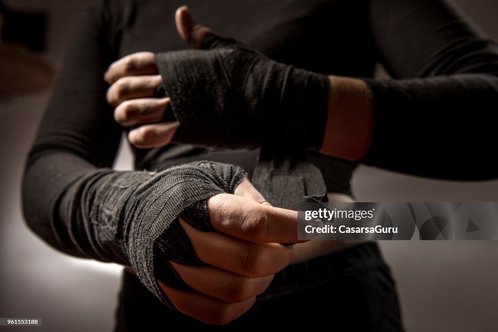 Young Woman Boxer Tying Protective Bandage Around Her Wrists
