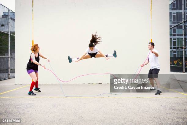 confident friends performing double dutch on street against wall - acrobatic activity photos et images de collection
