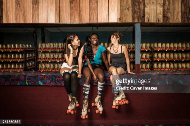 happy friends talking while relaxing against roller skates at club - all that skate 2014 stock pictures, royalty-free photos & images