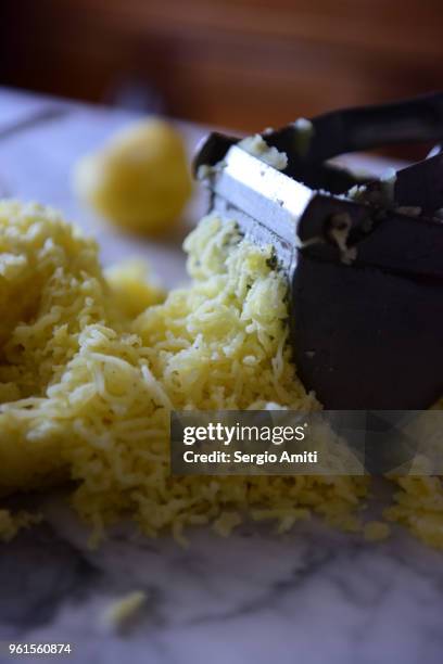 pressing a boiled potato through a steel potato ricer - potato masher stockfoto's en -beelden