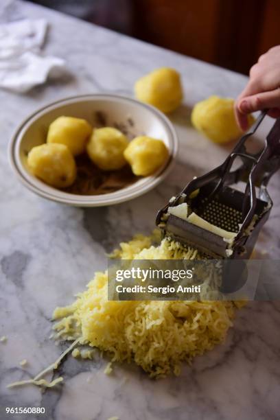 pressing a boiled potato through a steel potato ricer - potato masher bildbanksfoton och bilder