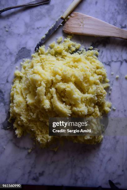 riced boiled potatoes on a table next to a wooden spatula - aardappelstamper stockfoto's en -beelden