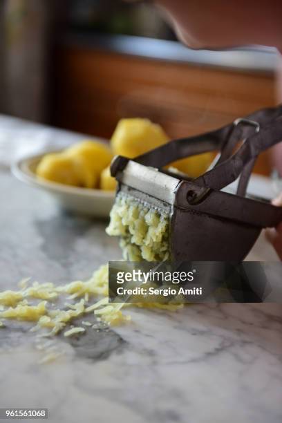 pressing a boiled potato through a steel potato ricer - potato masher stock pictures, royalty-free photos & images