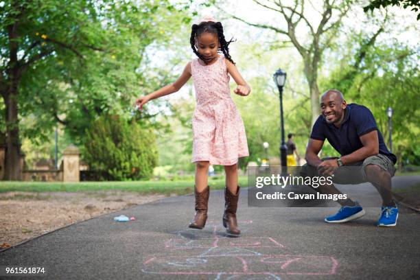 father and daughter playing hopscotch on road at park - hopscotch stock-fotos und bilder