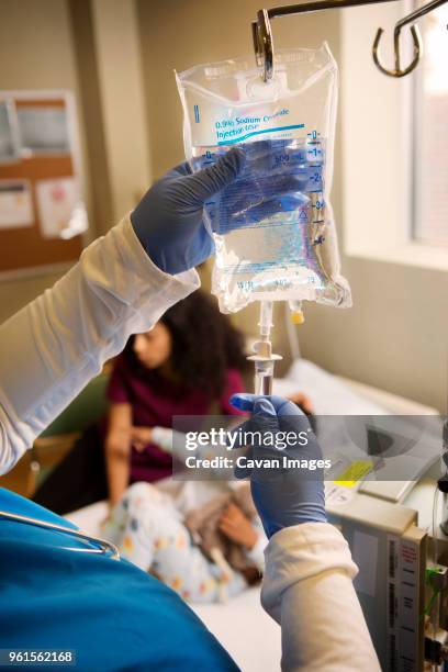 nurse setting iv drip in hospital - infuus met een fysiologische zoutoplossing stockfoto's en -beelden