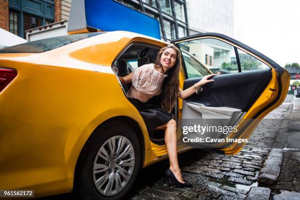 smiling beautiful woman getting out of yellow car on cobbled street - gå i land bildbanksfoton och bilder