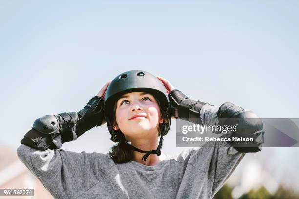 11 year old girl rollerblading in helmet, knee pads and elbow pads - ellbogenschützer stock-fotos und bilder