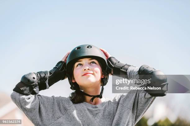 11 year old girl rollerblading in helmet, knee pads and elbow pads - sports helmet stock-fotos und bilder