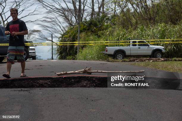 Resident of the Leilani Estates subdivision steps over a crack in Pahoa, Hawaii on May 22, 2018. - Authorities in Hawaii have warned of dangerous...