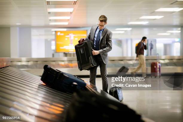 businessman picking up suitcase from baggage claim at subway station - baggage claim stock pictures, royalty-free photos & images