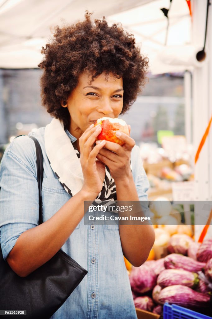 Portrait of woman eating apple in market