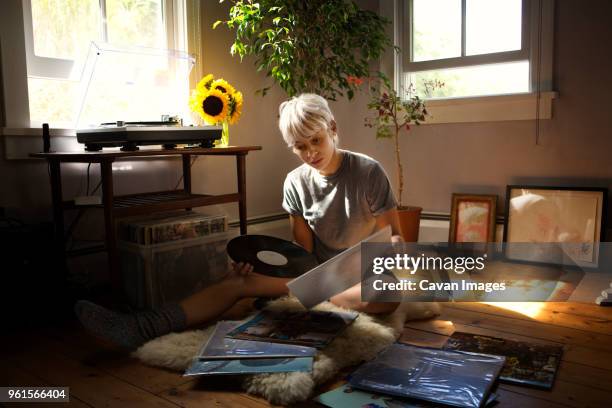 young woman looking at vinyl records while sitting on floor at home - platten stock-fotos und bilder