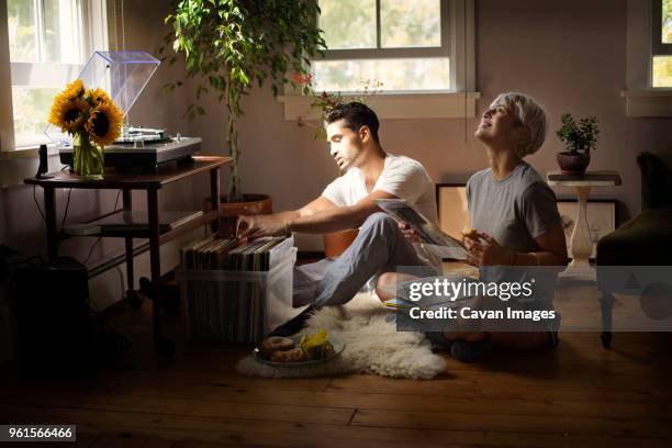 happy young couple choosing vinyl record at home - looking at a photo album stock-fotos und bilder