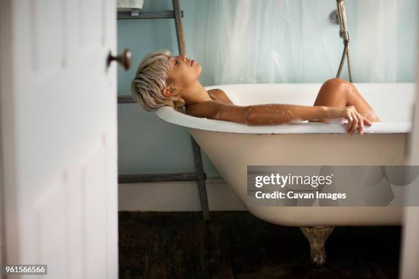 side view of woman relaxing in bathtub - frau badewanne stock-fotos und bilder