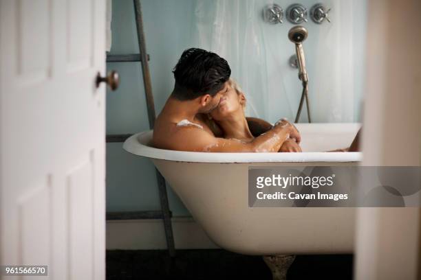 young couple kissing in bathtub at home - woman showering stock-fotos und bilder
