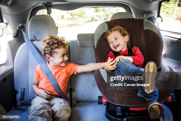 boy tickling brother while sitting in car - kid car seat stock-fotos und bilder