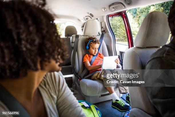 mother looking at son using laptop computer in car - child car tablet stock pictures, royalty-free photos & images