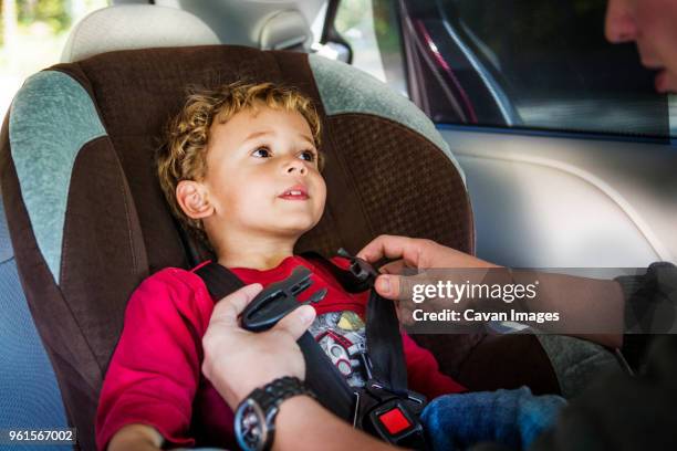 cropped image of father fastening safety belt of son - guy in car seat stockfoto's en -beelden