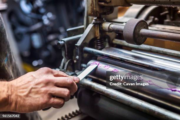cropped image of hand applying purple ink on printing roller at workshop - printing roller stock pictures, royalty-free photos & images