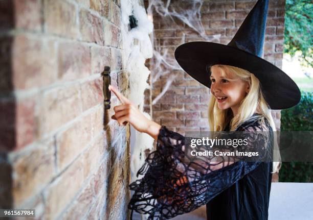 girl dressed in witch costumes ringing door bell - door bell fotografías e imágenes de stock