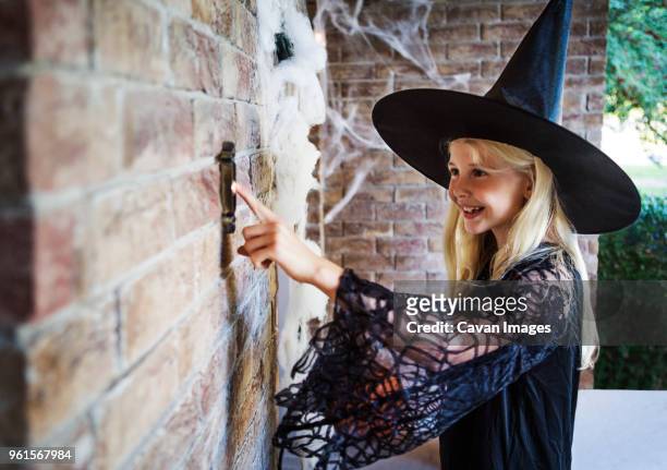 girl dressed in witch costumes ringing door bell - girl doorbell stock pictures, royalty-free photos & images