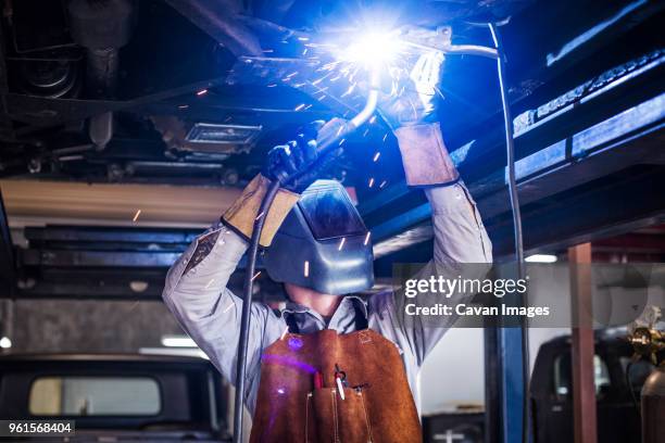mechanic welding car in auto repair shop - auto mechaniker stock-fotos und bilder