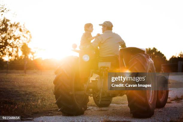 rear view of father driving tractor while looking at daughter - girl driving tractor stock pictures, royalty-free photos & images
