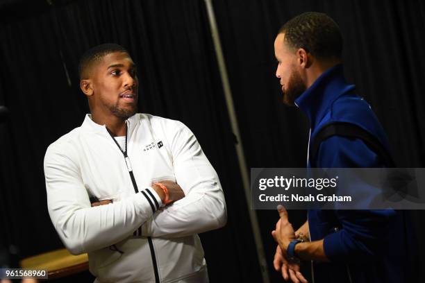 Stephen Curry of the Golden State Warriors talks to Anthony Joshua after the game against the Houston Rockets in Game Four of the Western Conference...